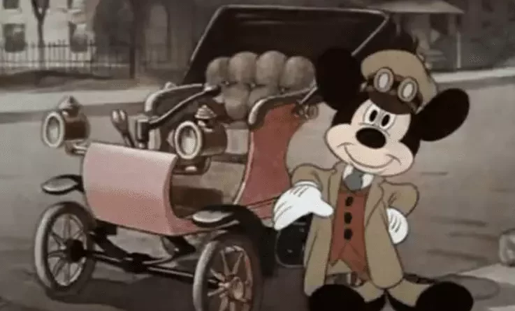 Mickey Mouse posant à côté d'une des premières voitures des années 1890 dans un des dessins animés abordant la Révolution industrielle.